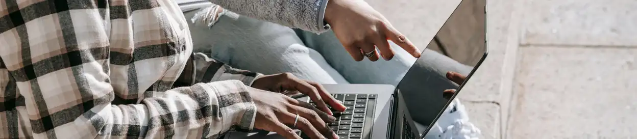 someone types on a laptop keyboard, another person points at the screen