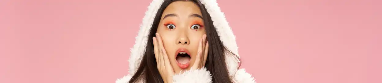 A woman looks shocked in front of a pink background