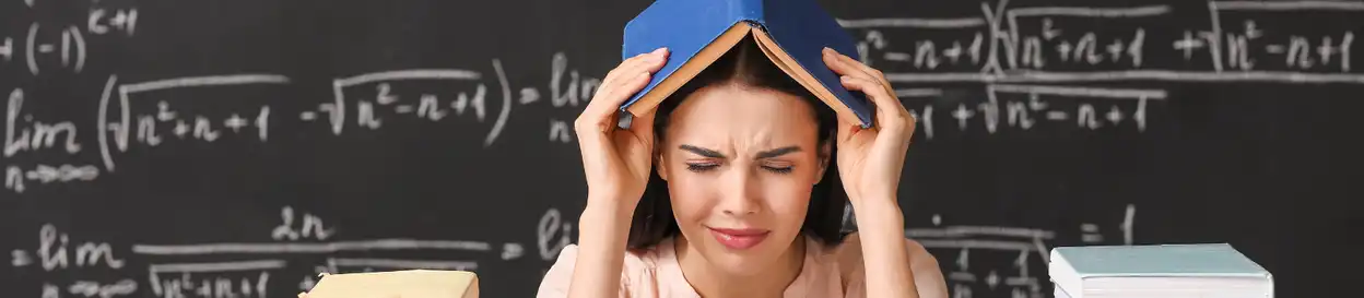 A stressed teacher takes cover under a blue book