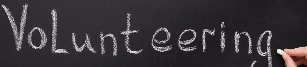 The word "Volunteering" written in chalk on a chalkboard