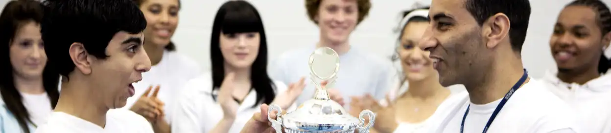 a student receives a trophy from their teacher